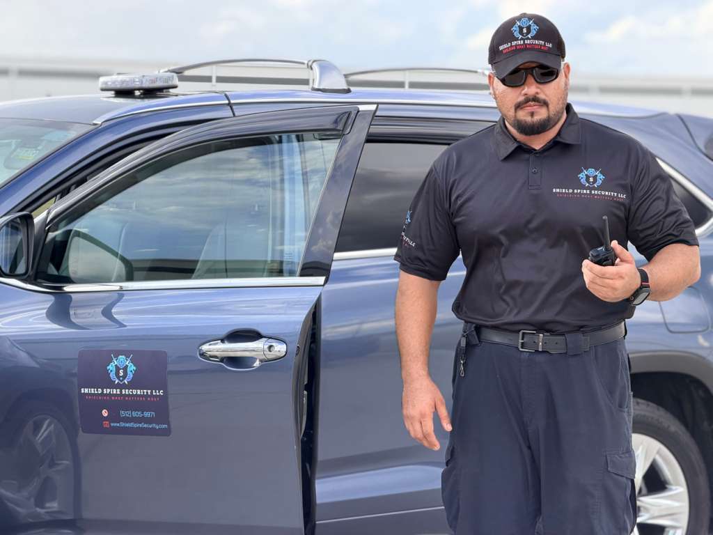 Shield Spire Security licensed officer on post beside a marked patrol vehicle at an industrial facility in the Greater Austin Area of Texas during a multi-week corporate asset protection deployment.